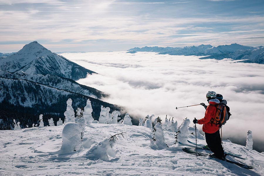 Skiløbere på bjergtop over skyerne i Canada